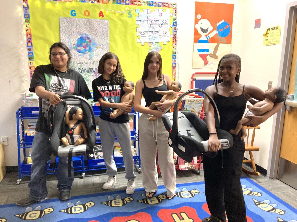 From left to right: Early Childhood Development students Abrian Rico, Kayla Hawel, Savanah Barclay, and Lysis Hills hold their robotic dolls at Chandler High School on August 20, 2025.